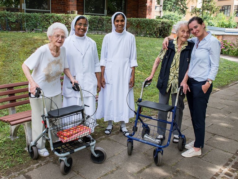 Gruppenbild im Garten: zwei Bewohnerinnen mit Rollator, zwei Ordensschwestern und vermutlich eine Angehörige