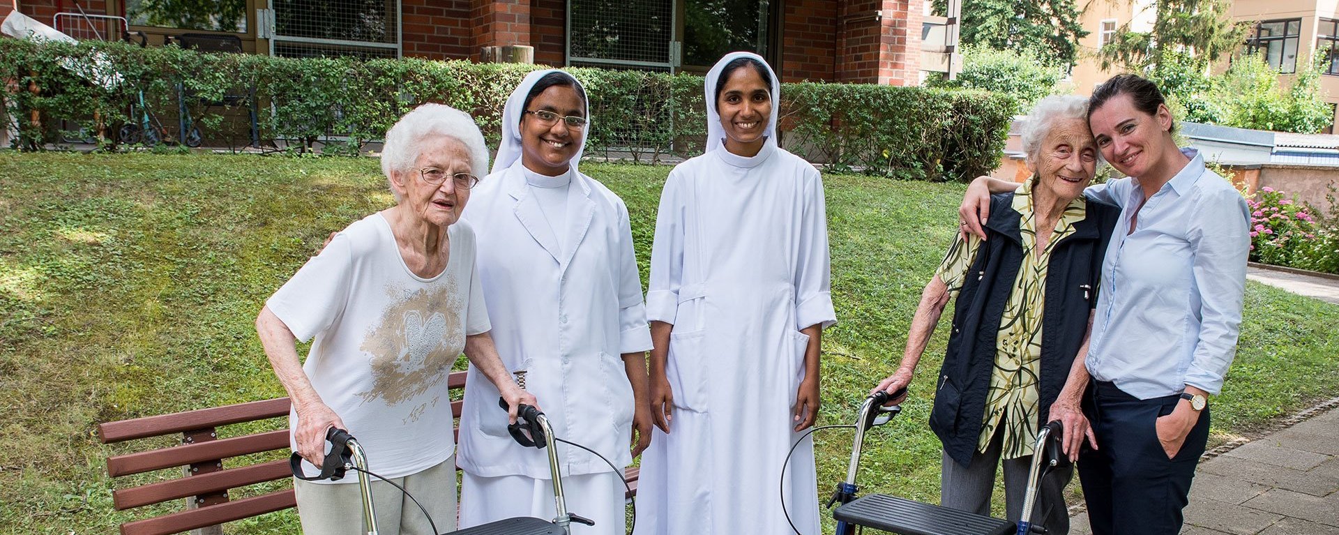 Gruppenbild im Garten: zwei Bewohnerinnen mit Rollator, zwei Ordensschwestern und vermutlich eine Angehörige